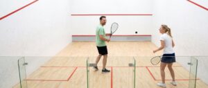 Een rally op een squashbaan, gezien door de glazen achterwand