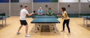 Vier spelers in een dubbelrally aan een tafeltennistafel